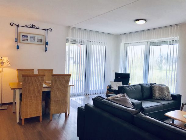 Foto Wohnzimmer mit Sofa und Esstisch sowie den Terassentüren mit Blick auf die Wiese