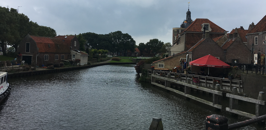 Foto Gracht, links und rechts Häuser, vorne Bäume und darüber Wolken