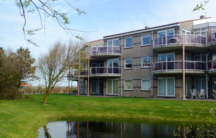 Foto Wassergracht im Vordergrund dahinter Wiese und die Residence Juliana