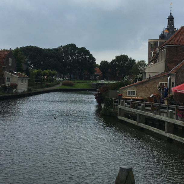 Foto Gracht, links und rechts Häuser, vorne Bäume und darüber Wolken