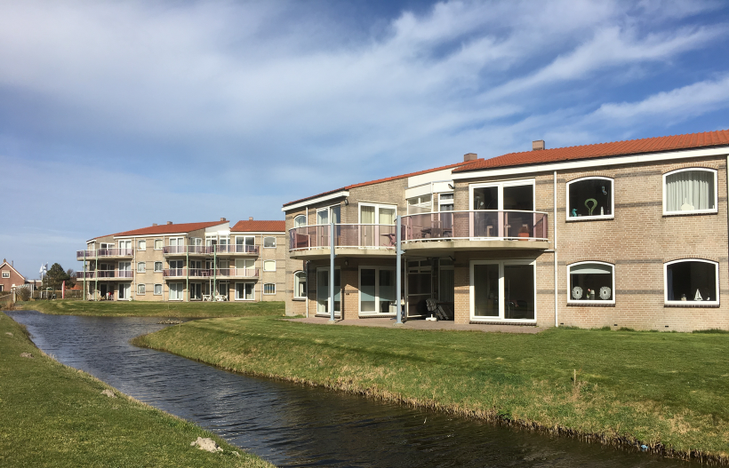 Foto Häuser der Residence Juliana davor eine Wiese mit Wassergracht darin