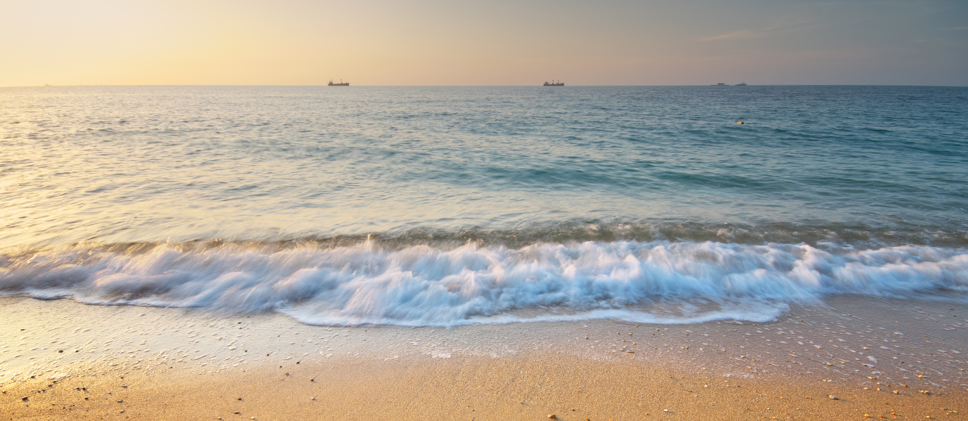 Foto vorne unten Strand mit Wellen darüber Meer im Sonnenuntergang