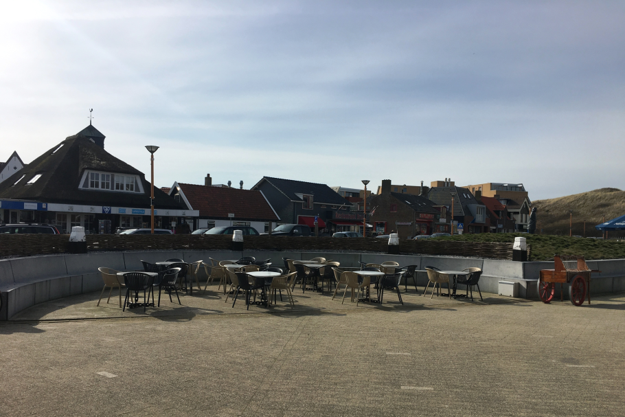 Foto Dorfplatz mit Tischen und Stühlen, im Hintergrund Häuser