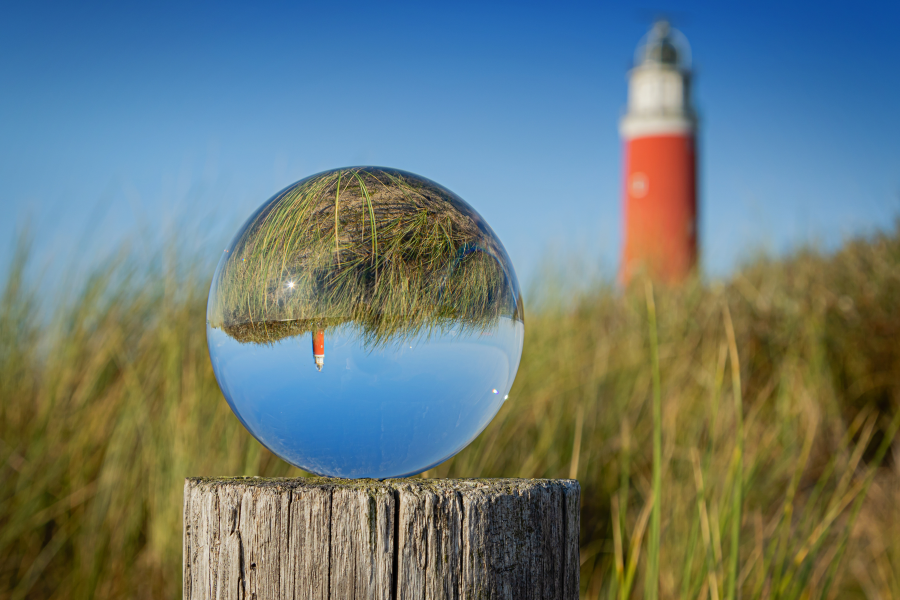 Foto Leuchtturm im Hintergrund blauer Himmel im Vordergrund Gras