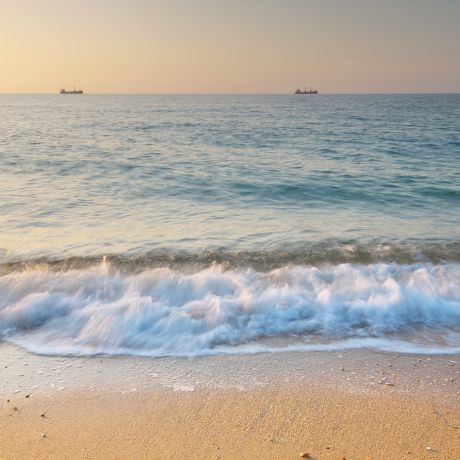 Foto vorne unten Strand mit Wellen darüber Meer im Sonnenuntergang