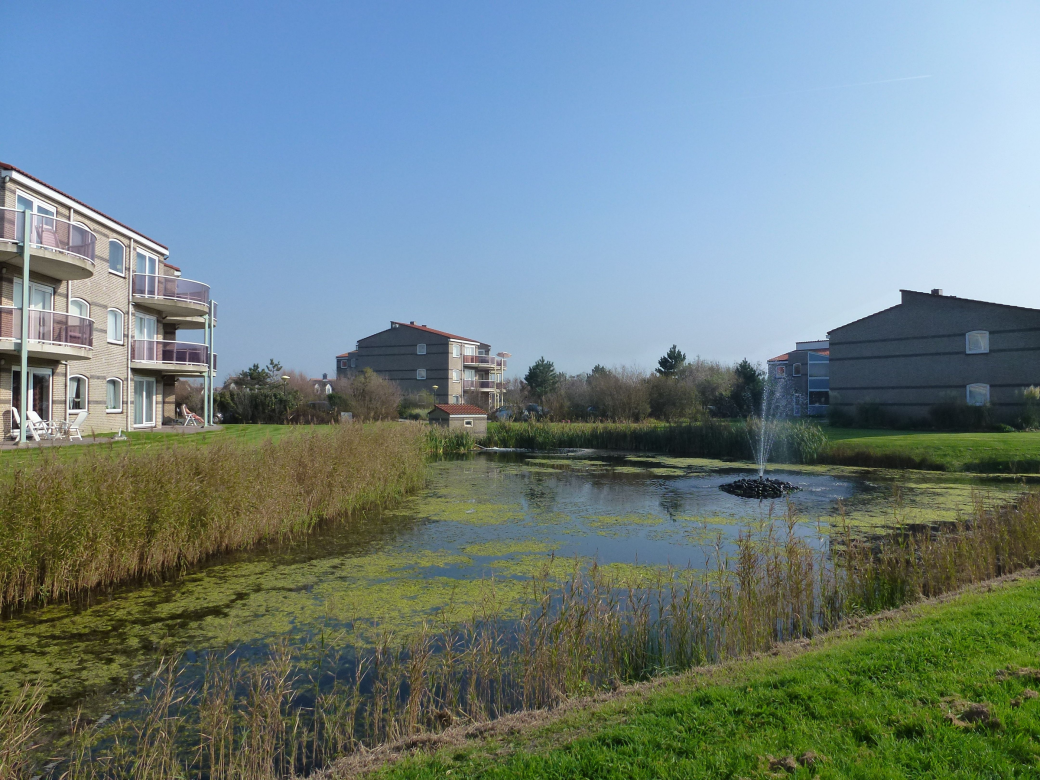 Foto Wassergracht vor den Häusern der Residence Juliana und darüber blauer Himmel